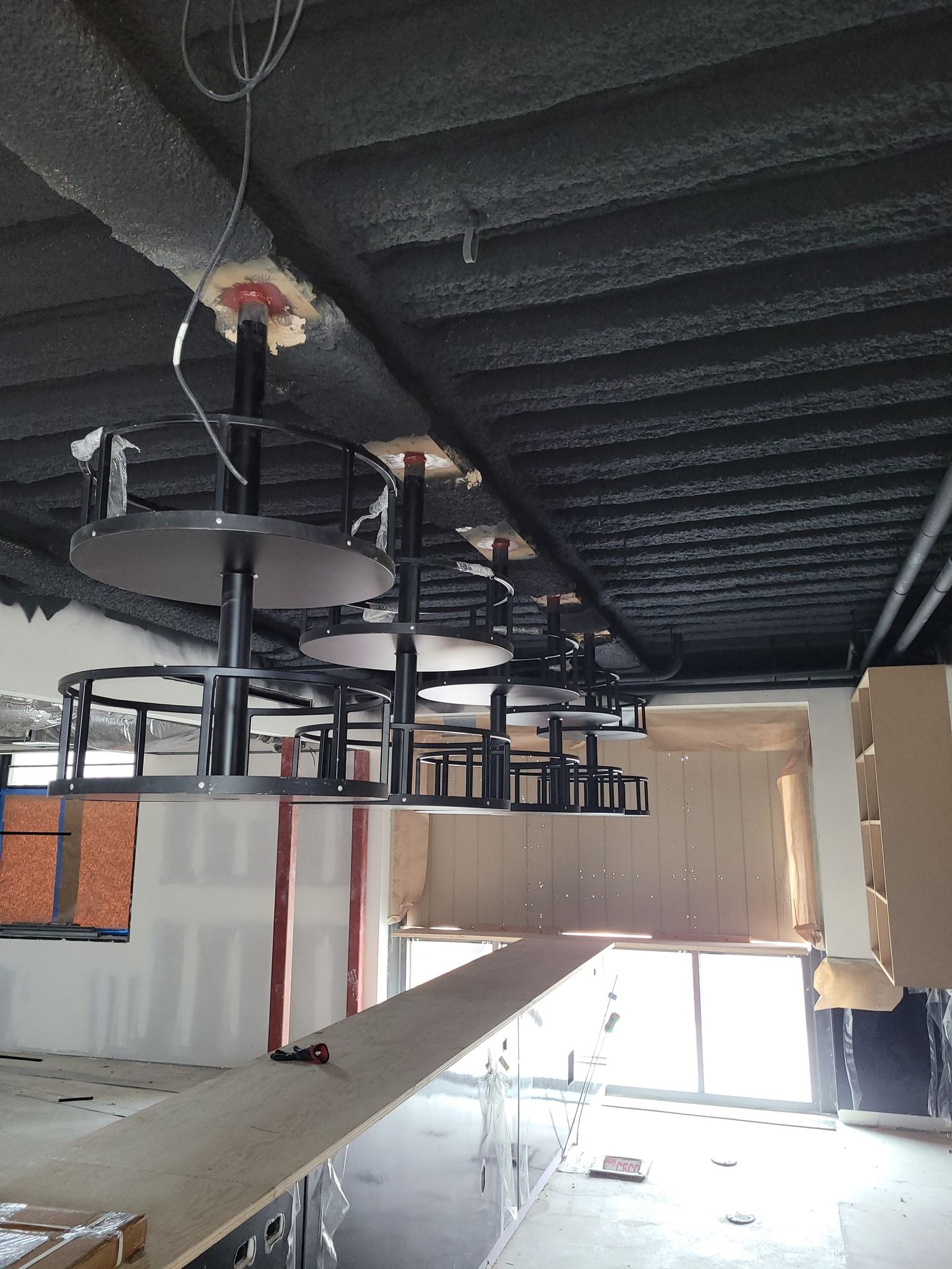 A building under construction with tables and chairs hanging from the ceiling
