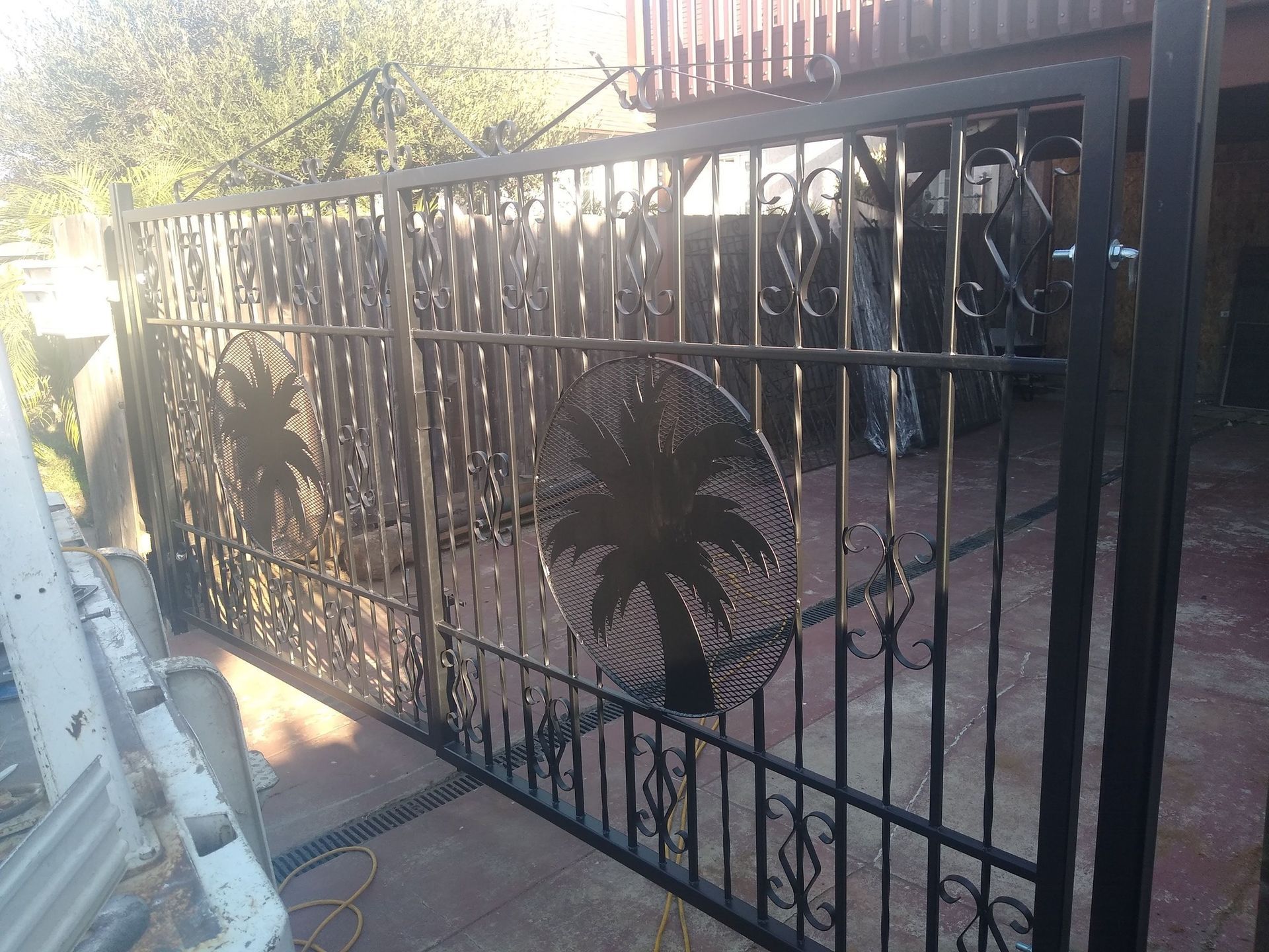 A black wrought iron gate with a palm tree design on it.