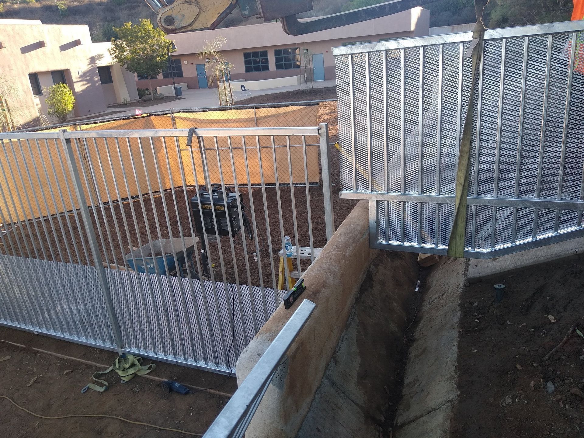 A metal fence is being built next to a building