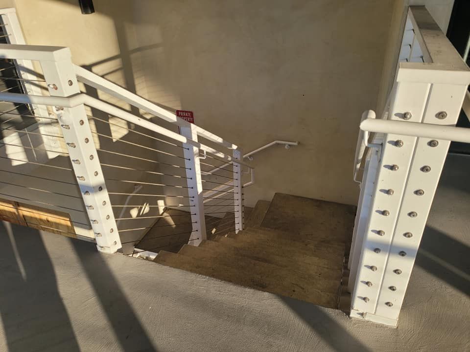 A staircase with a white railing and a concrete floor