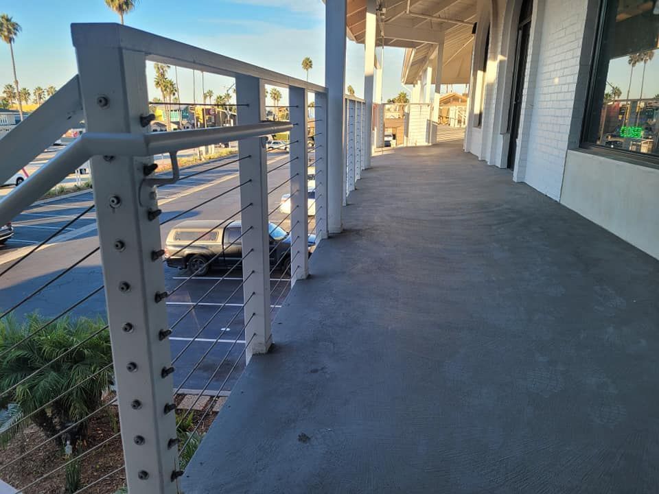 A balcony with a white railing and a parking lot in the background.