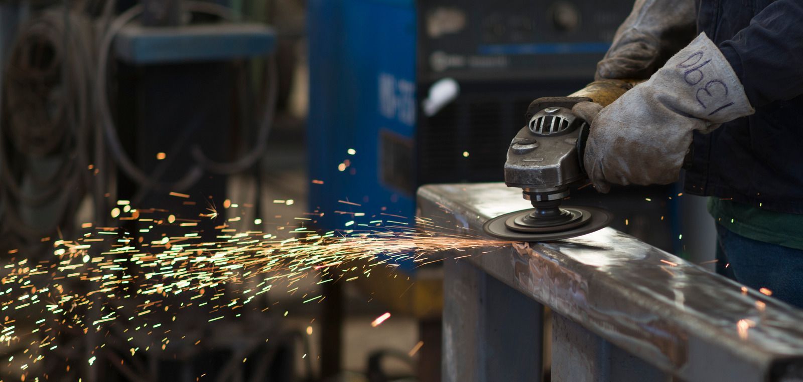A person is grinding a piece of metal in a factory.
