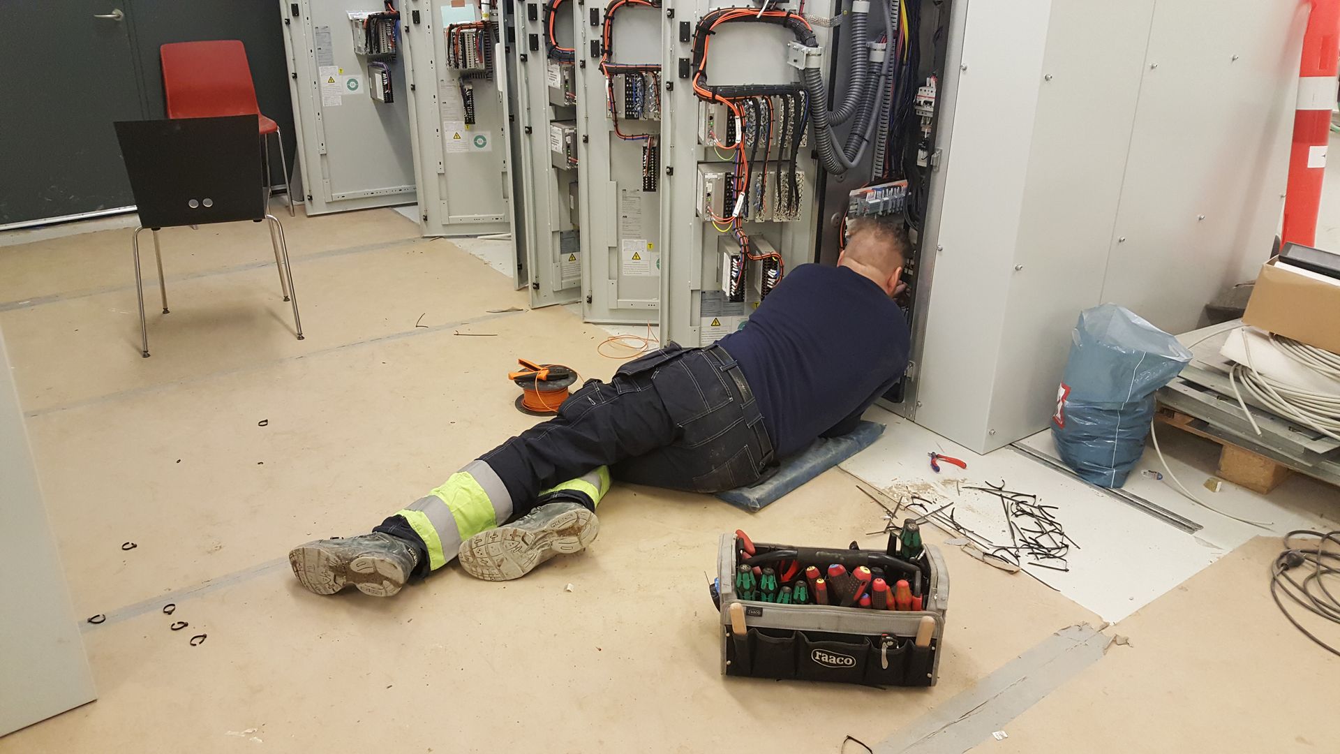 En mand ligger på gulvet og arbejder på en el-dåse.