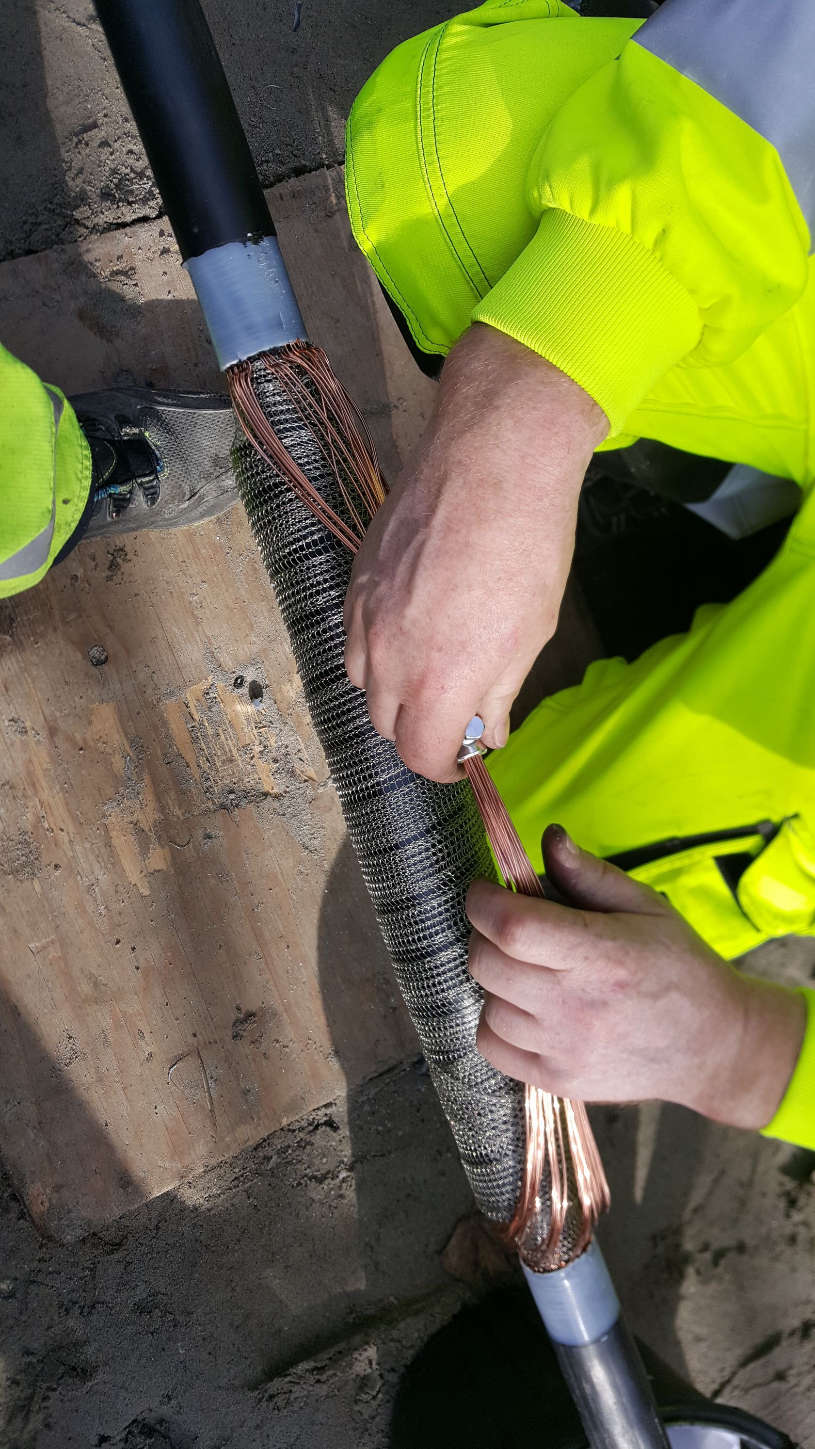 En mand i en gul jakke arbejder på en kobbertråd.