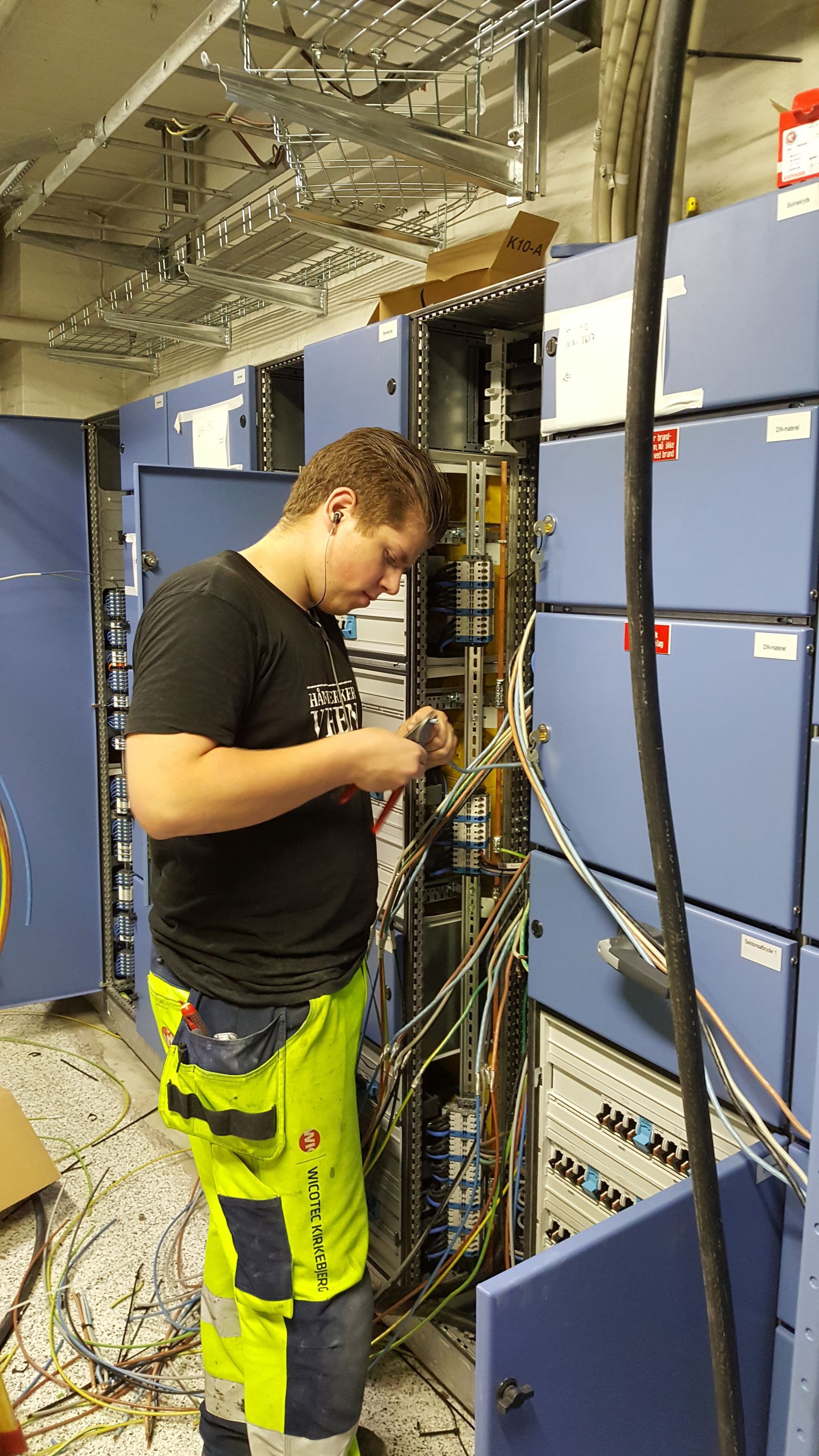 En mand i gule bukser arbejder på en computer i et værelse.