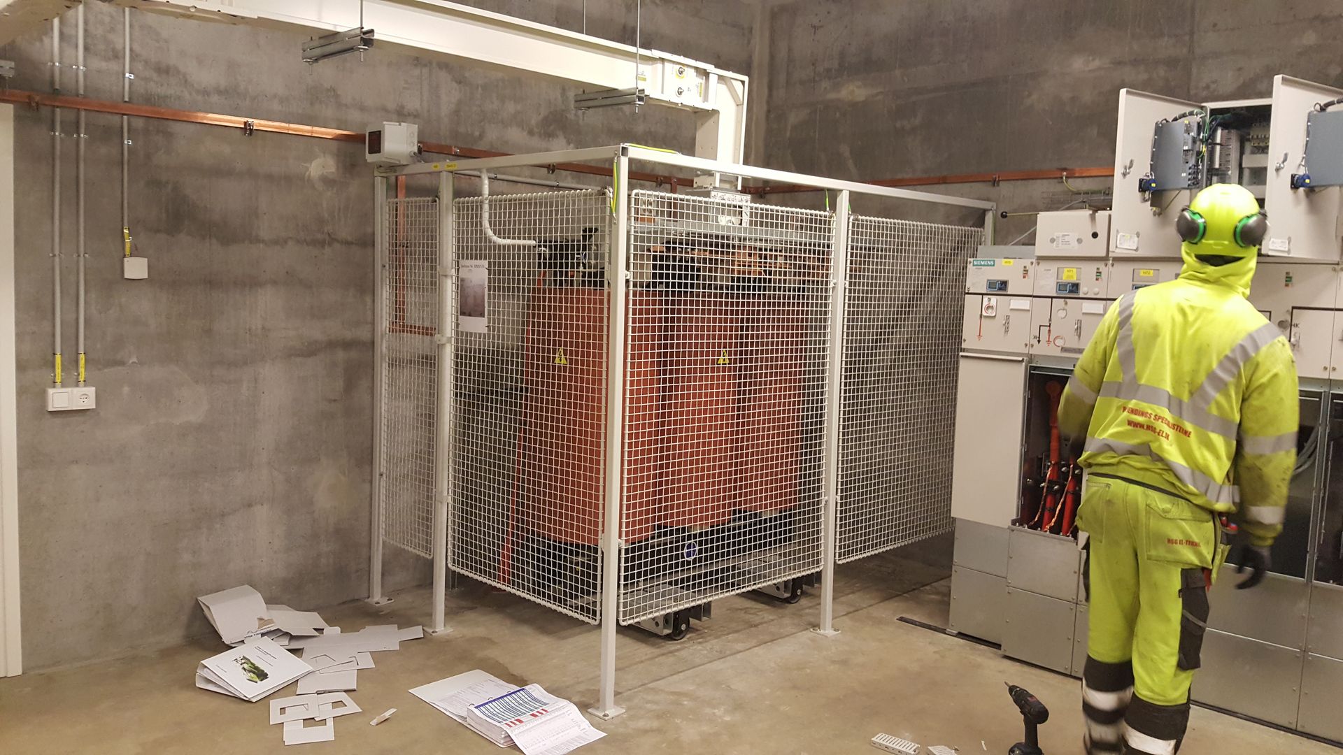 En mand i en gul sikkerhedsdragt står i et rum.