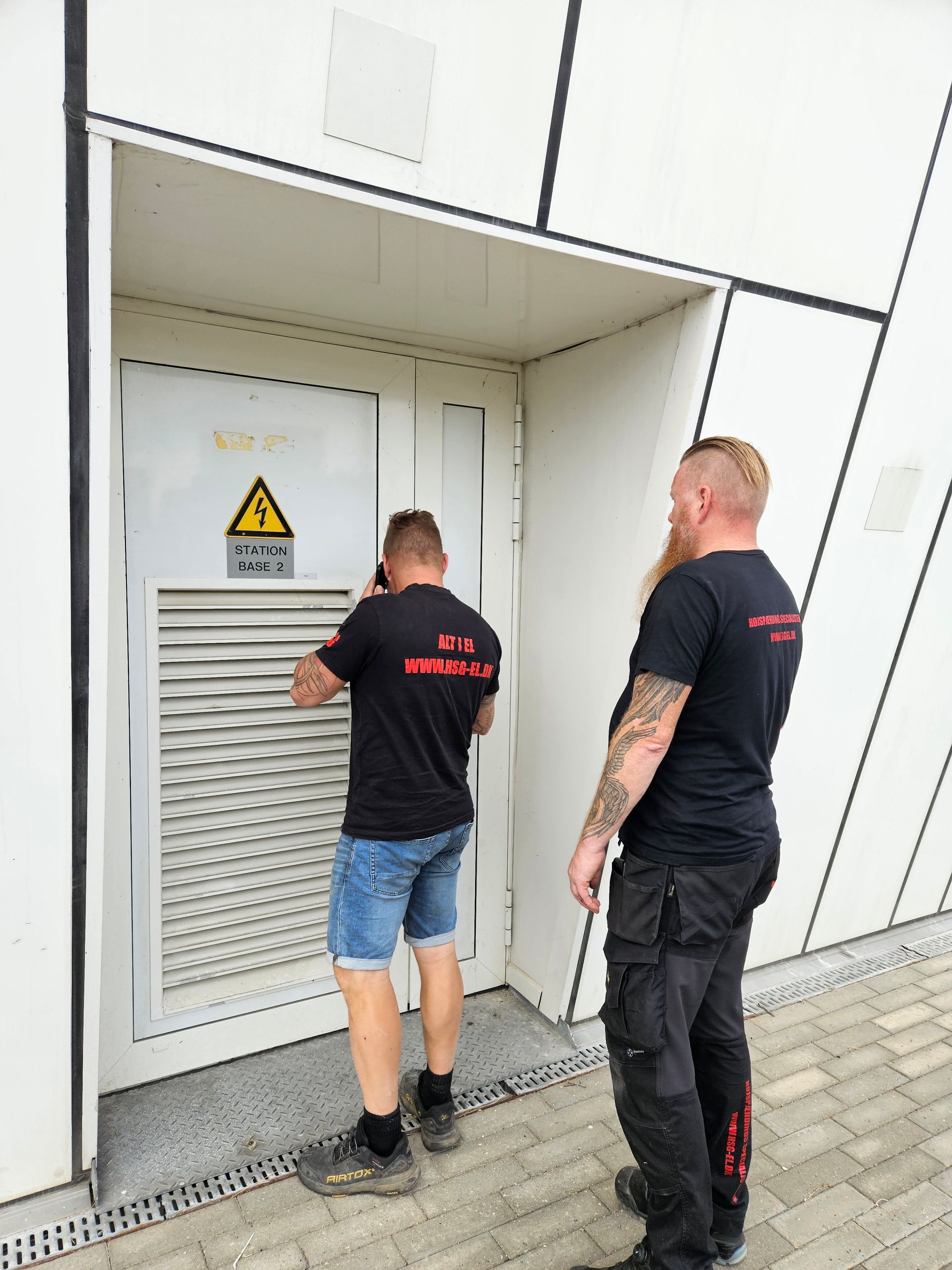 To mænd står foran en dør med et advarselsskilt på.