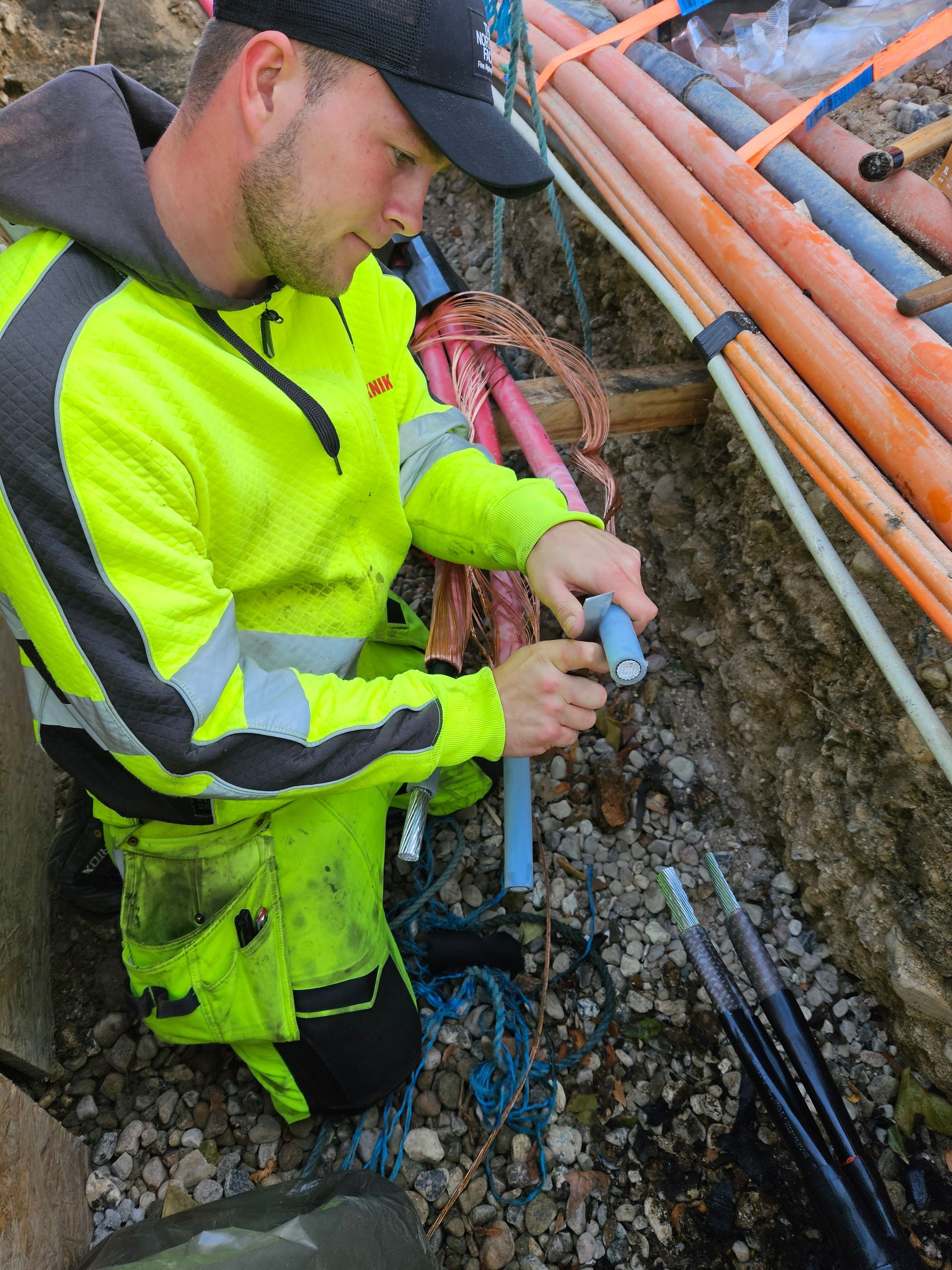 En mand i en gul jakke arbejder på et rør