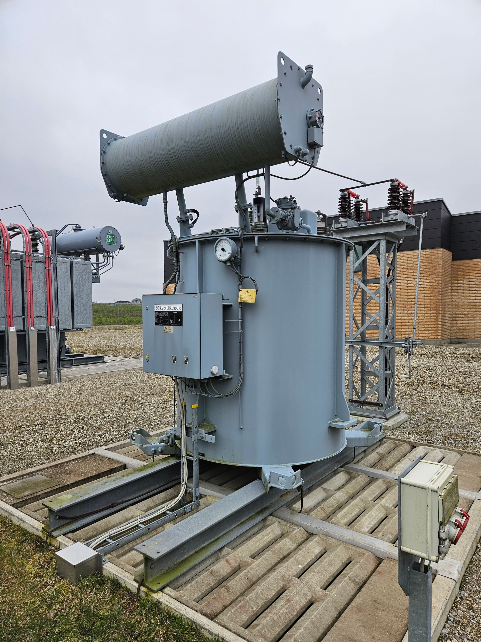 En stor transformer står oven på en træplatform på en mark.