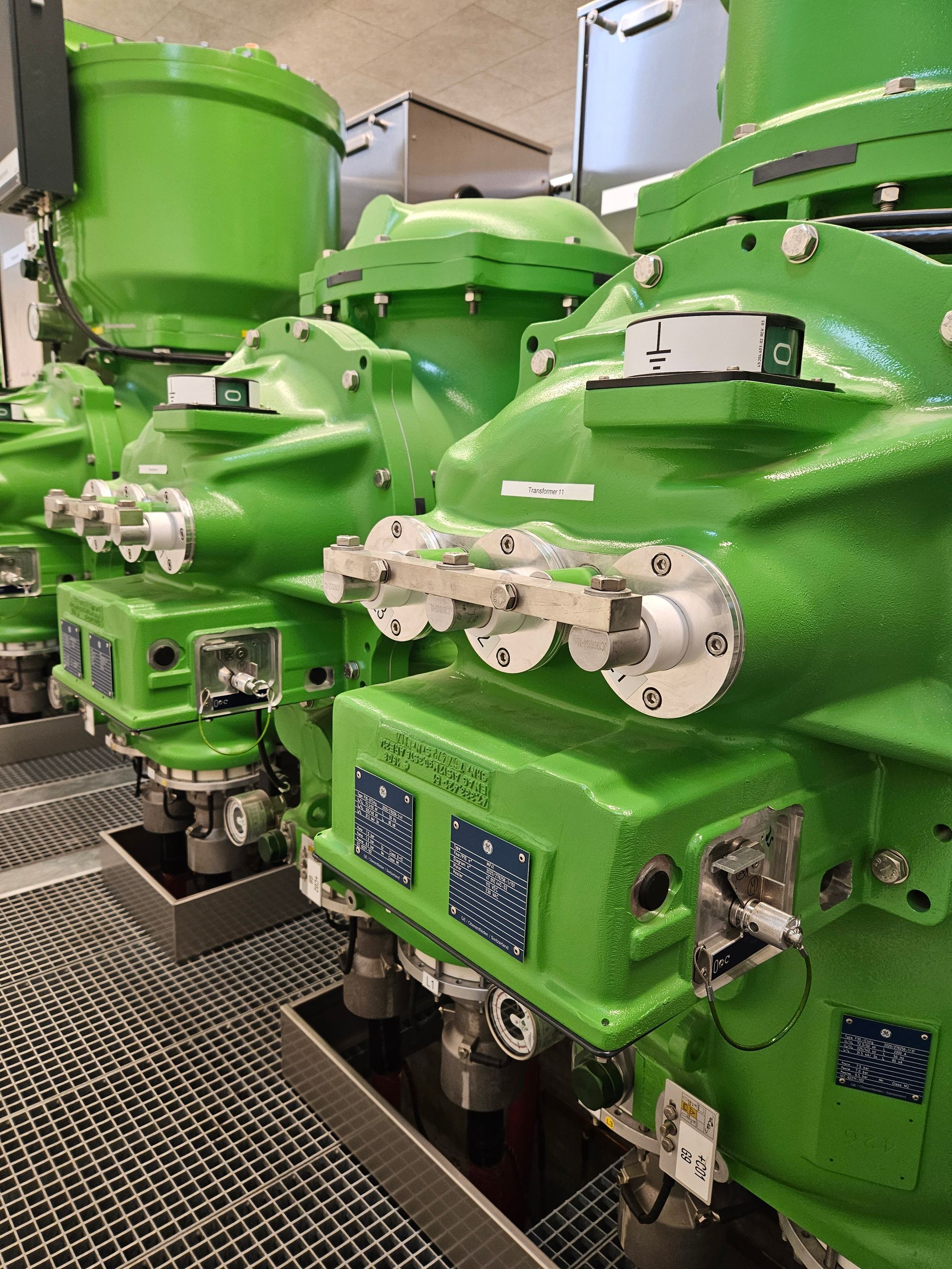 En række grønne maskiner står opstillet i et rum.