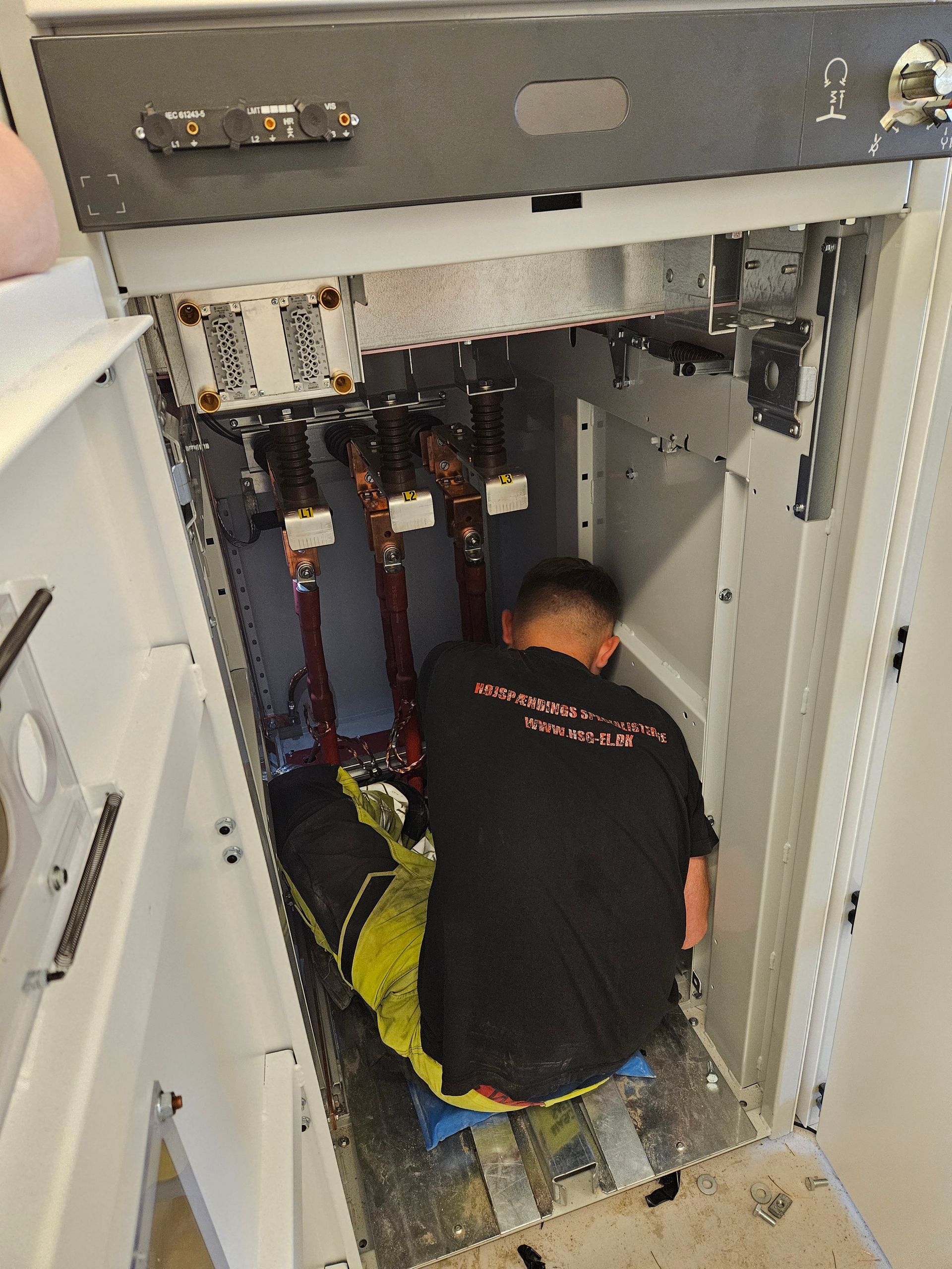 En mand i en sort skjorte arbejder på en elektrisk boks