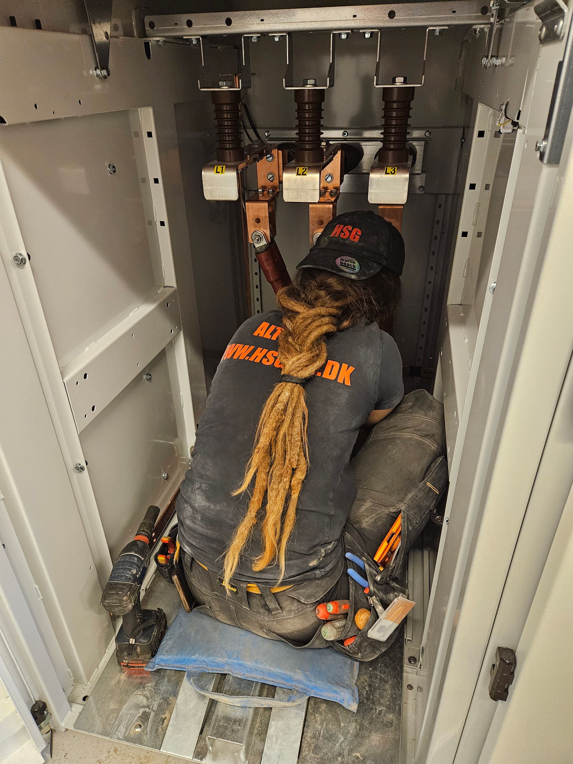 En mand med dreadlocks knæler ned i et skab.