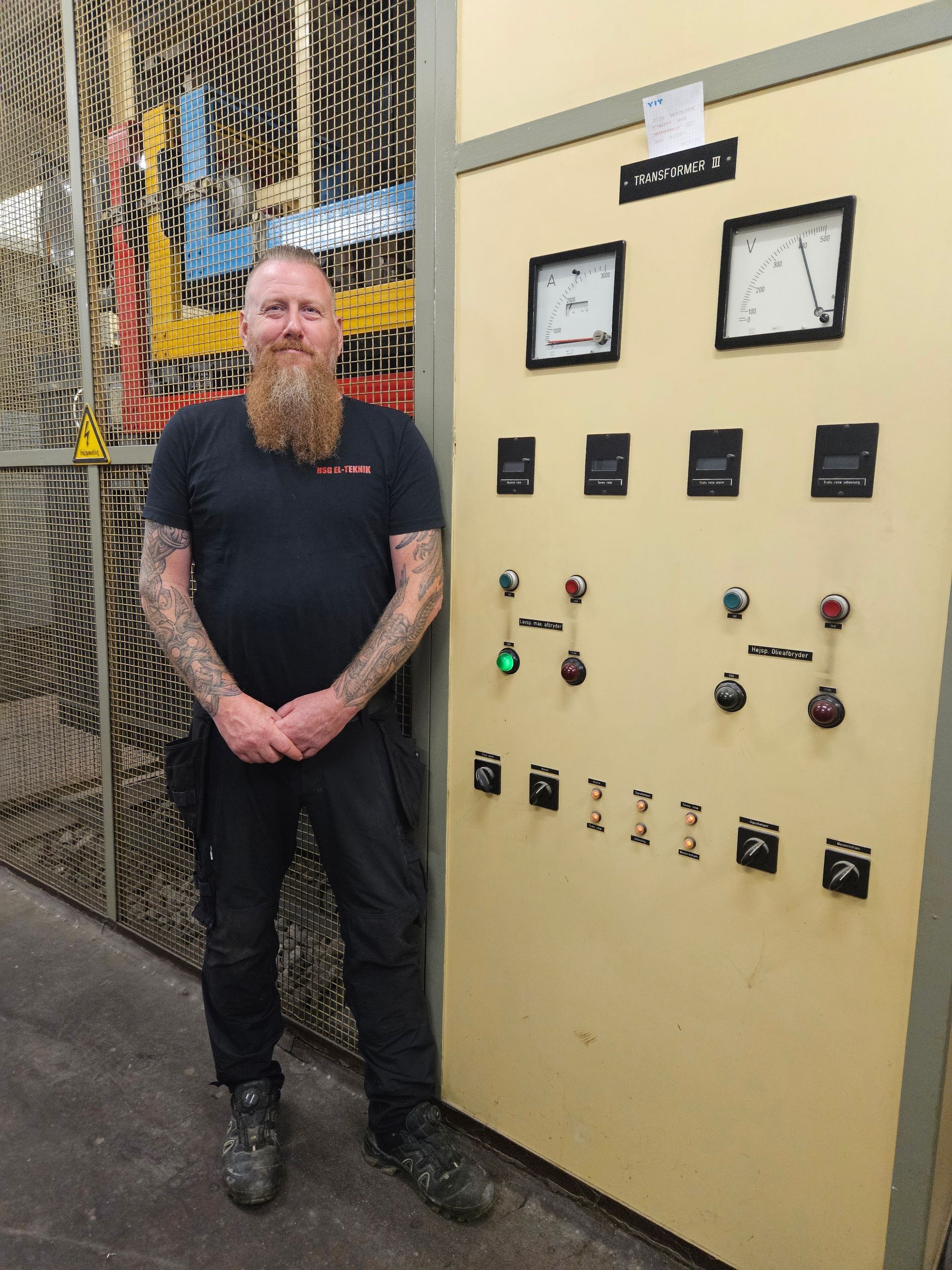 En mand med skæg står foran et kontrolpanel