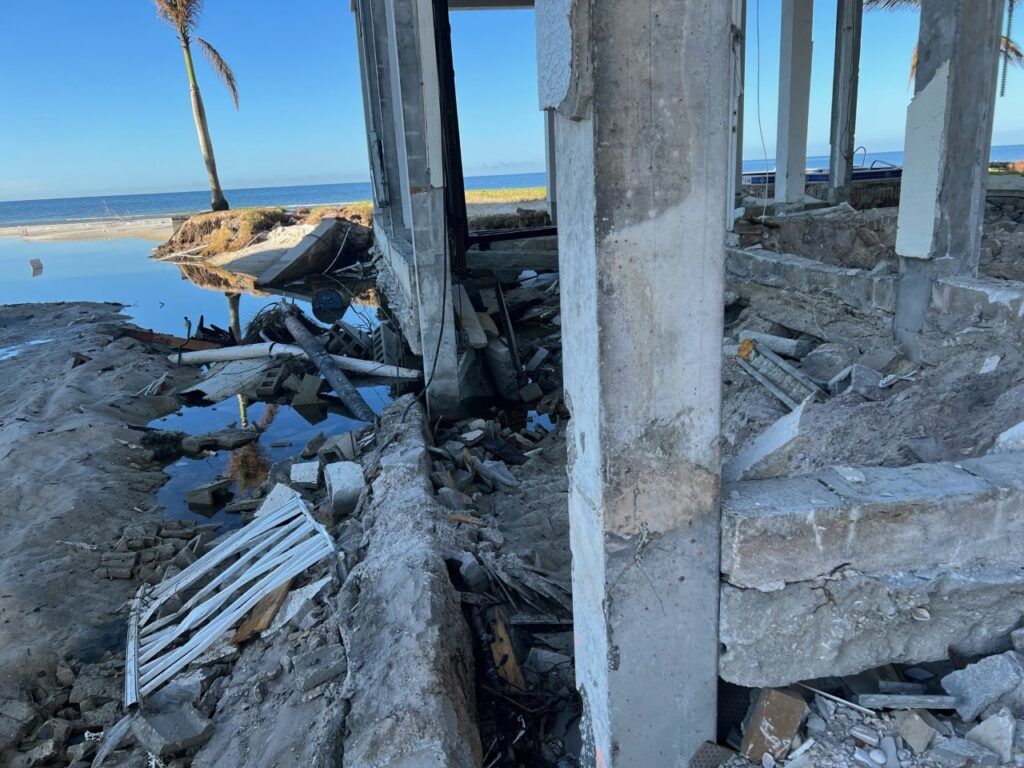 A concrete structure is being demolished on the beach.