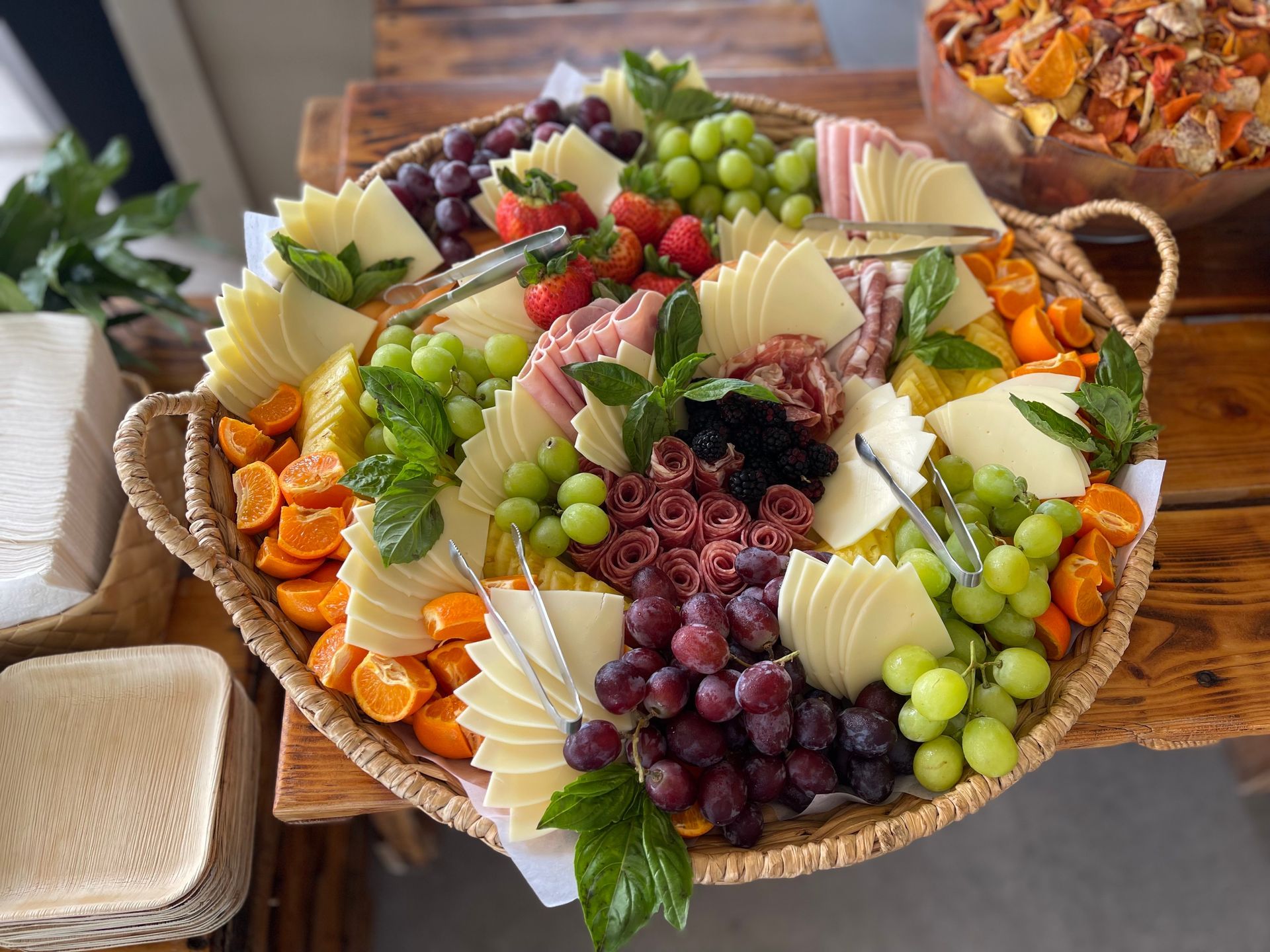 A wicker basket filled with fruit and cheese on a wooden table.