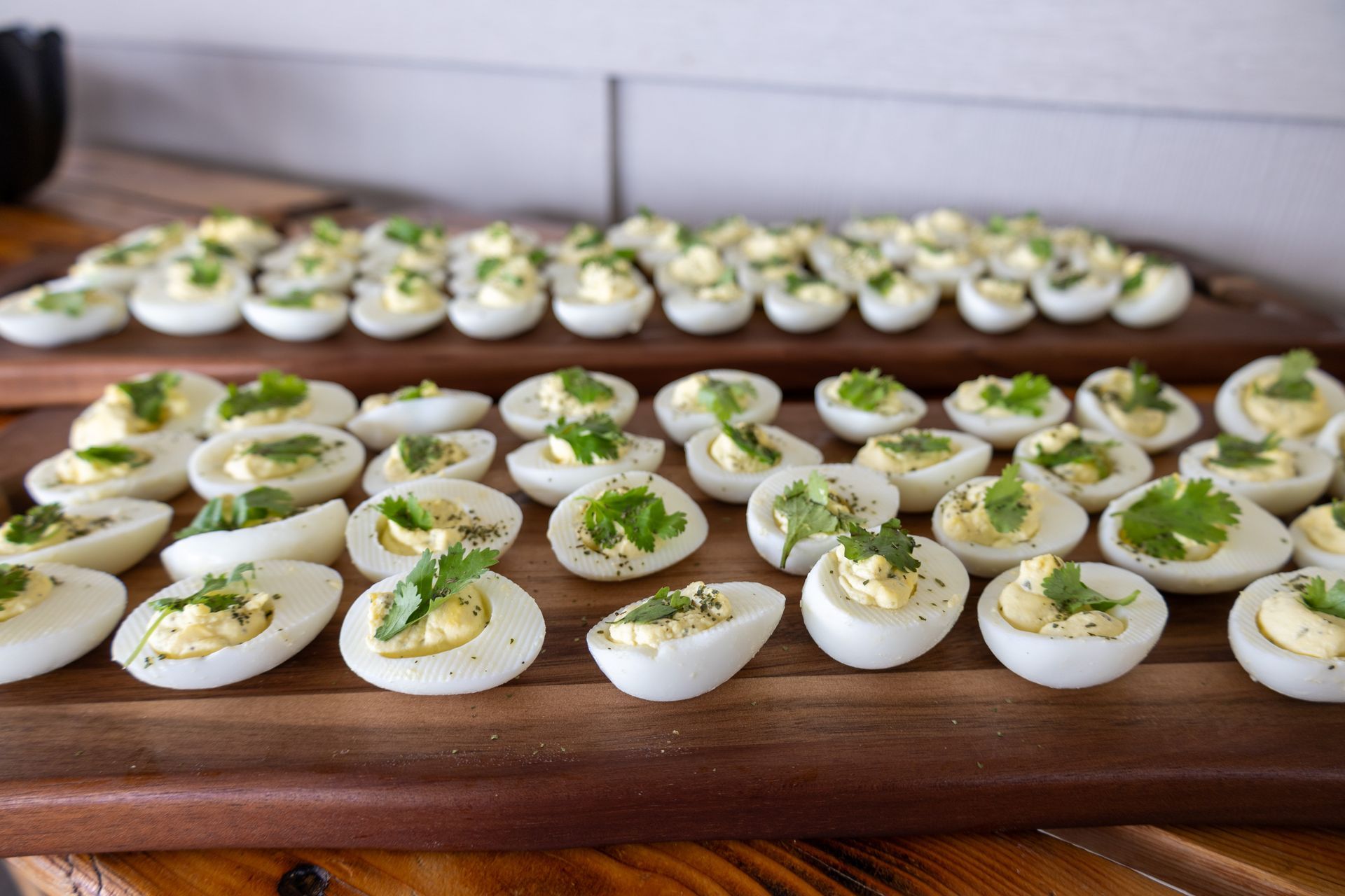 A wooden cutting board topped with hard boiled eggs and parsley.