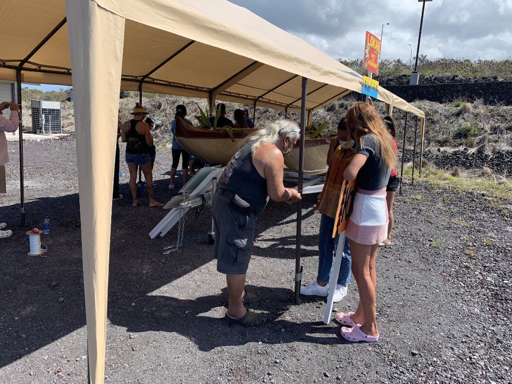 A group of people are standing under a tent.