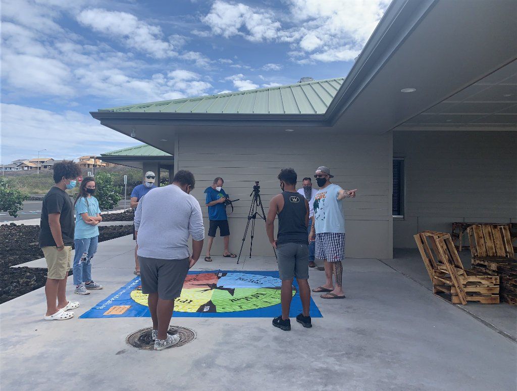 A group of people are standing around a large map on the ground.