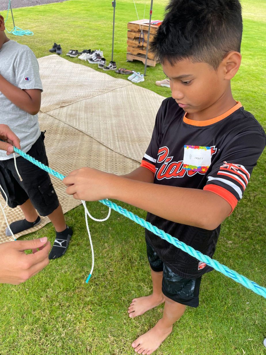 A young boy is playing with a rope in the grass.