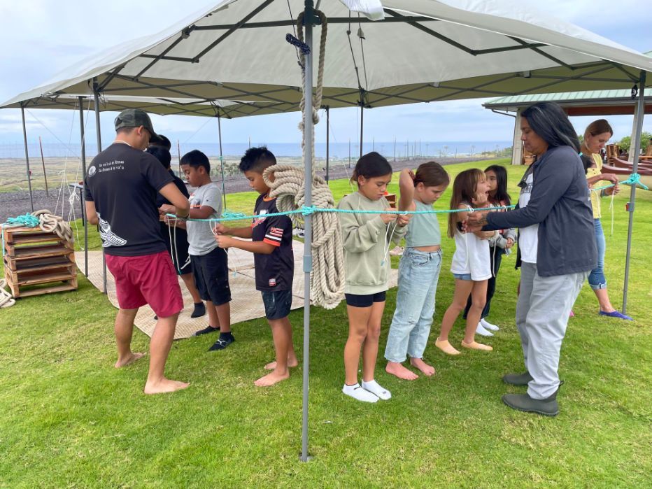 A group of children are standing in a row under a tent.