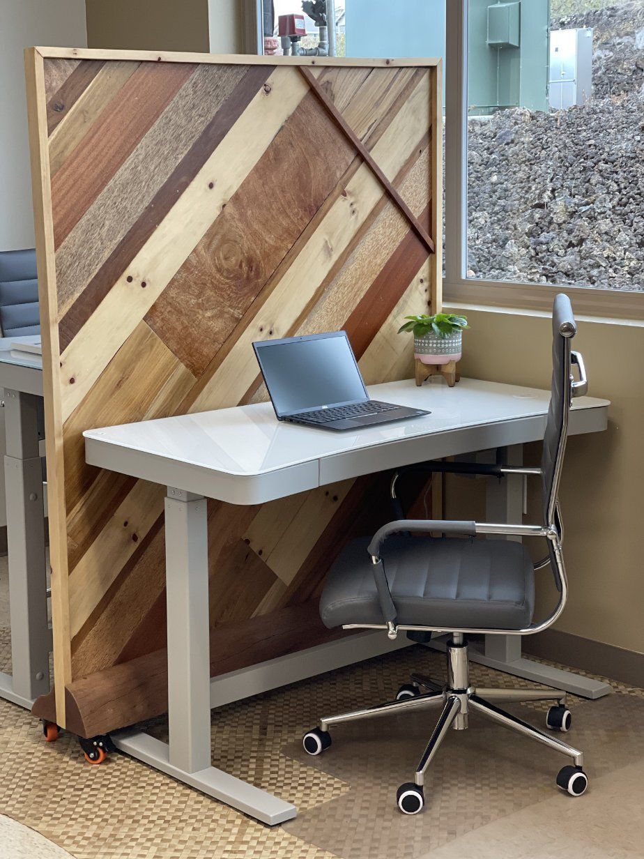 A laptop computer is sitting on a desk in front of a wooden wall.