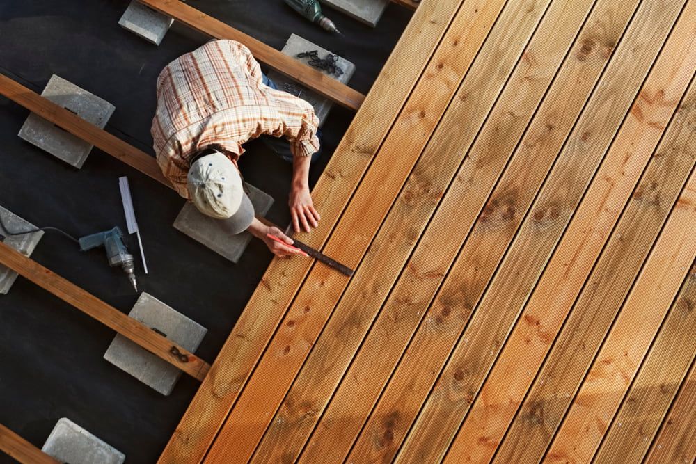 A Man Is Measuring A Piece Of Wood With A Tape Measure — Corbett Brothers Flooring In Woy Woy, NSW