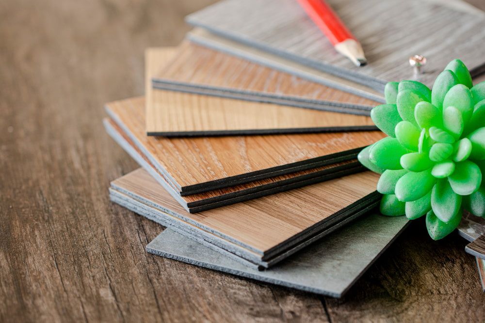 A Stack Of Wooden Flooring Samples With A Pencil And A Plant On A Wooden Table — Corbett Brothers Flooring In Woy Woy, NSW