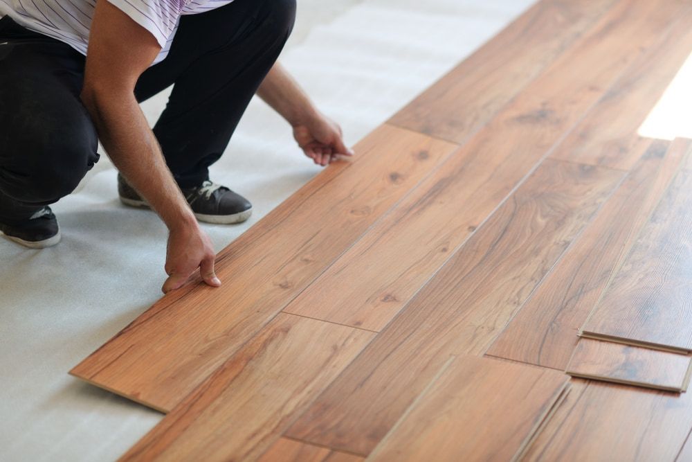 A Person Is Installing A Wooden Floor In A Room — Corbett Brothers Flooring In Woy Woy, NSW