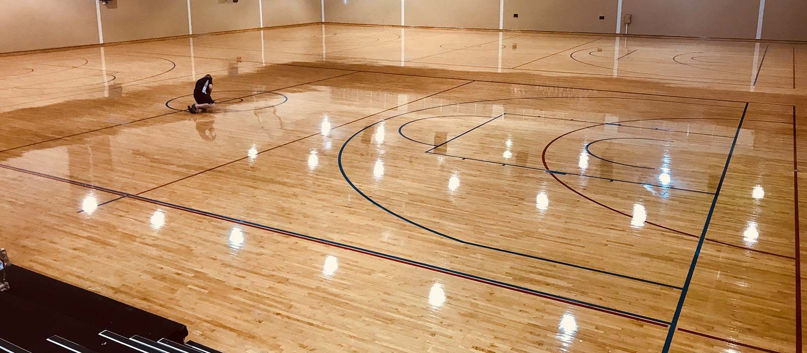 A person is cleaning a basketball court — Corbett Brothers Flooring In Woy Woy, NSW