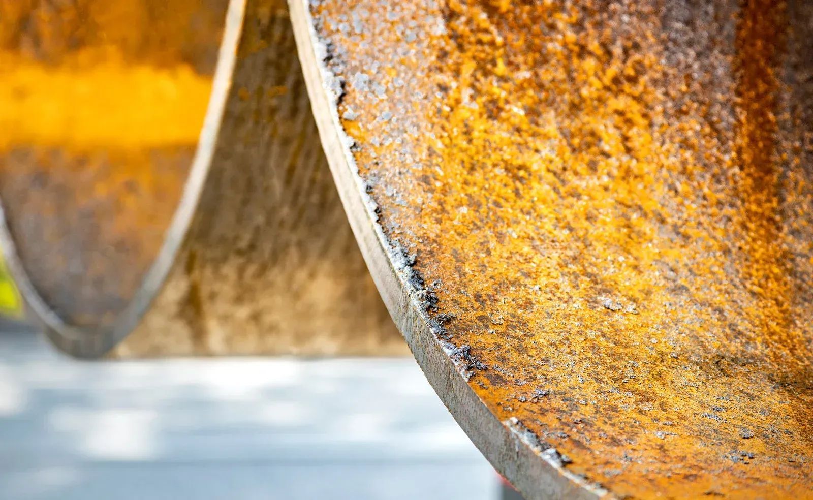 Close-up of rusty orange curved metal blades with weathered texture