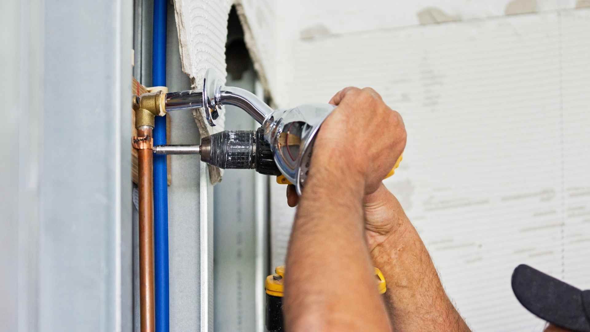 A man is fixing a pipe with a wrench.