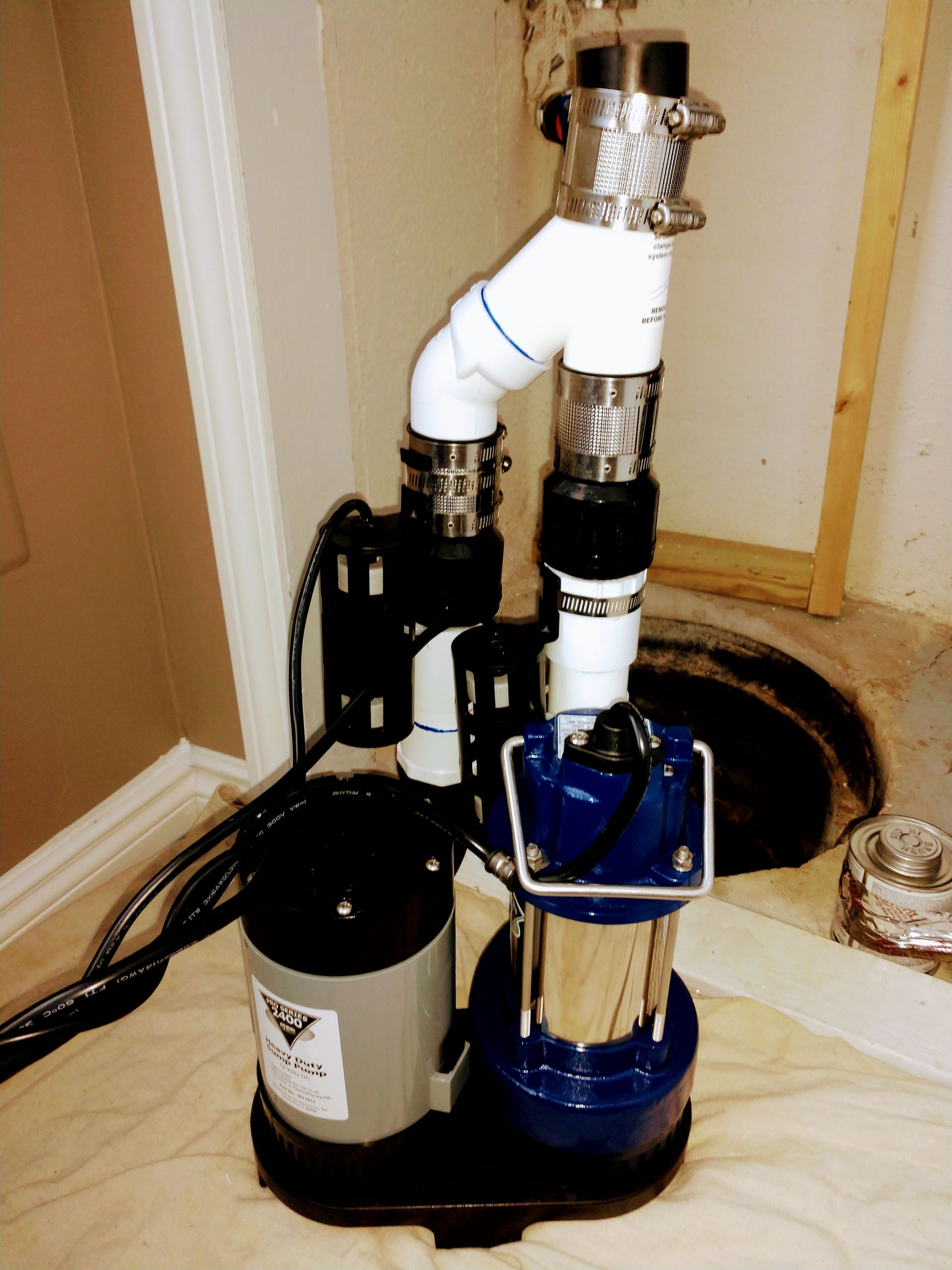 A blue and silver pump is sitting next to a hole in the floor.