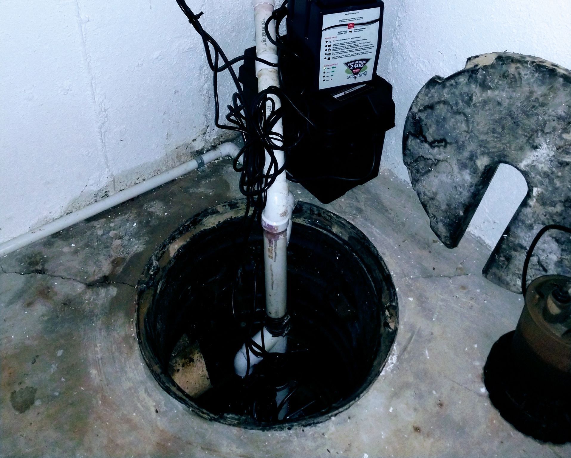 A basement pump is sitting in a hole in the floor
