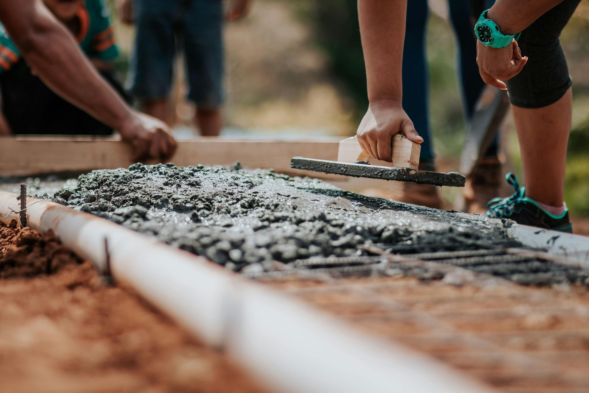 People smoothing concrete with a trowel at a construction site.