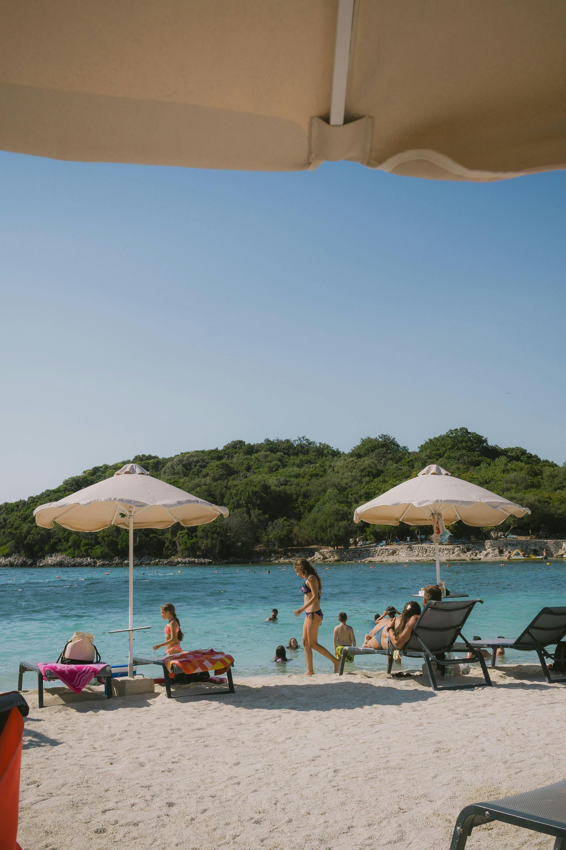 People sit on a terrace overlooking the sea at sunset, enjoying drinks.