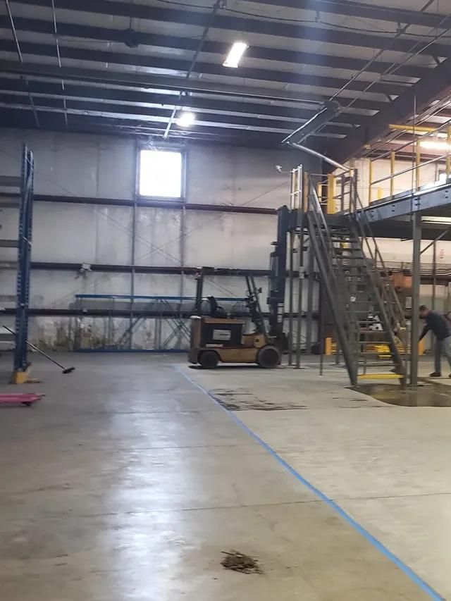 A forklift is parked in the middle of a large warehouse.