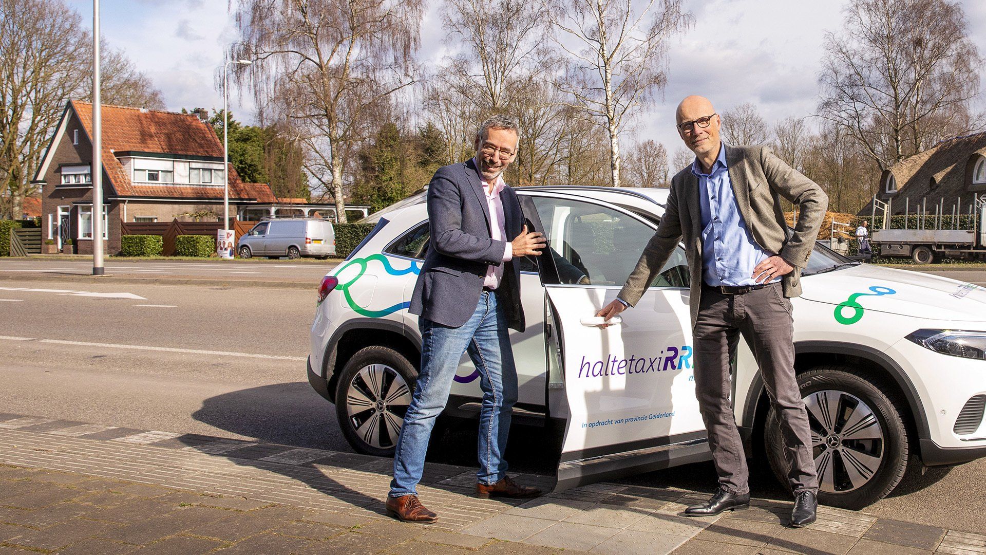 Jan van der Meer bezoekt coördinatiecentrum haltetaxiRRReis. Jan van der Meer (gedeputeerde) en Paul Pietersen (directeur Qarin) stappen in de eerste haltetaxi.