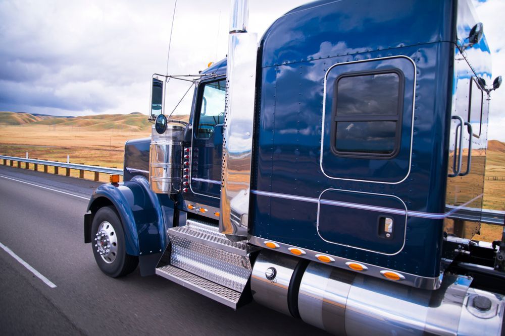 A Blue Semi Truck is Driving Down a Highway — Aust. Advanced Trailer Sales & Service In Kununurra, WA