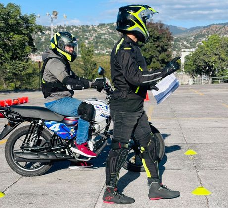 Dos hombres viajan en motocicletas en un estacionamiento.