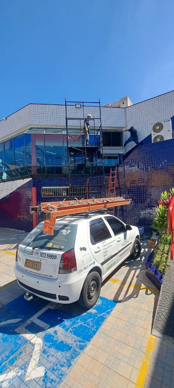 Técnico instalando câmera de segurança na parede externa de uma casa