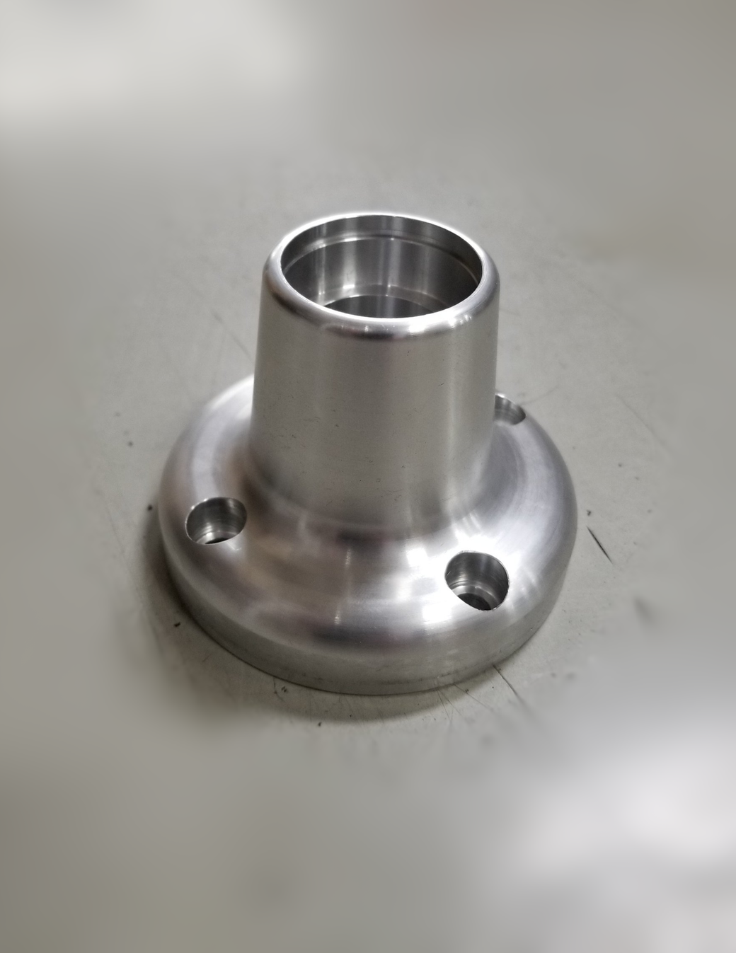 A stainless steel flange is sitting on a table.