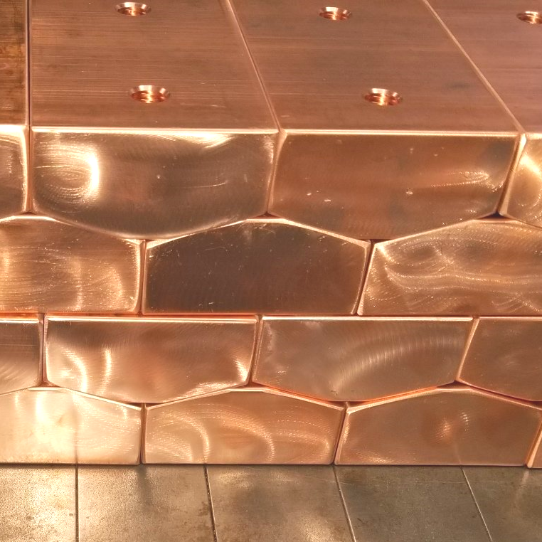 A stack of copper tiles with holes in them