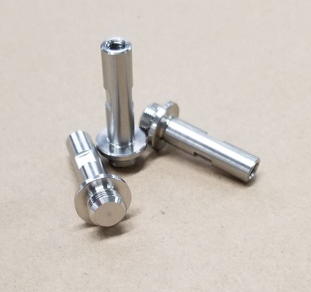 Three stainless steel screws are stacked on top of each other on a table.