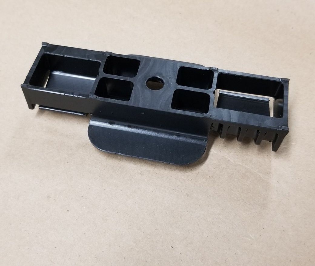 A black plastic item is sitting on a piece of cardboard