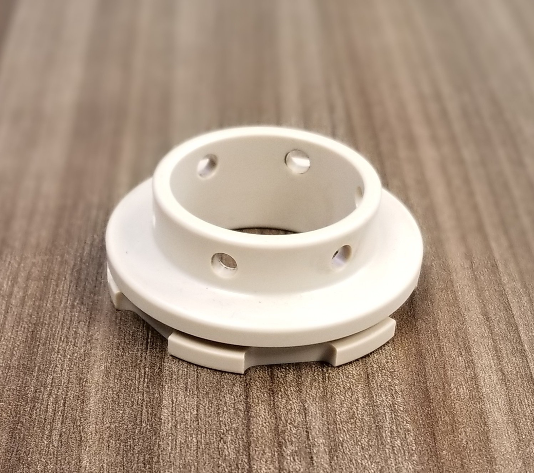 A white plastic ring with holes in it is sitting on a wooden table