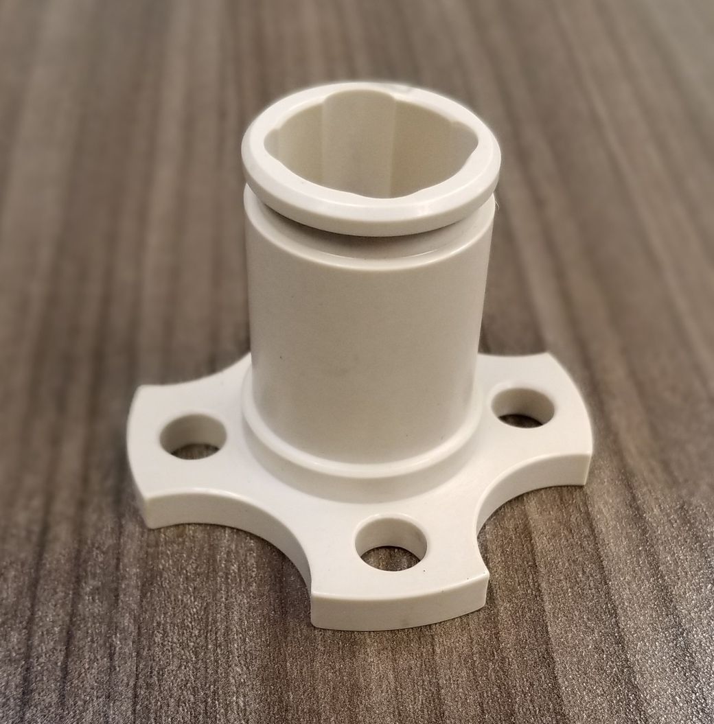 A white plastic object with holes in it is sitting on a wooden table