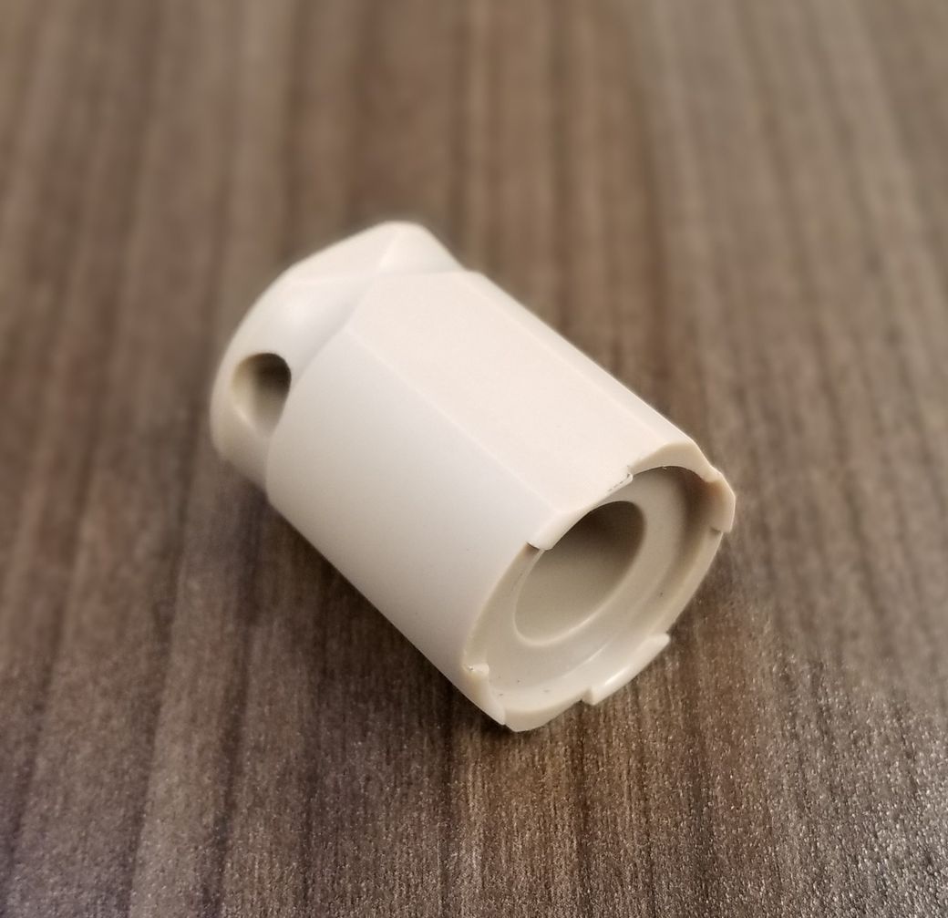 A white plastic cylinder with a hole in the middle sits on a wooden table