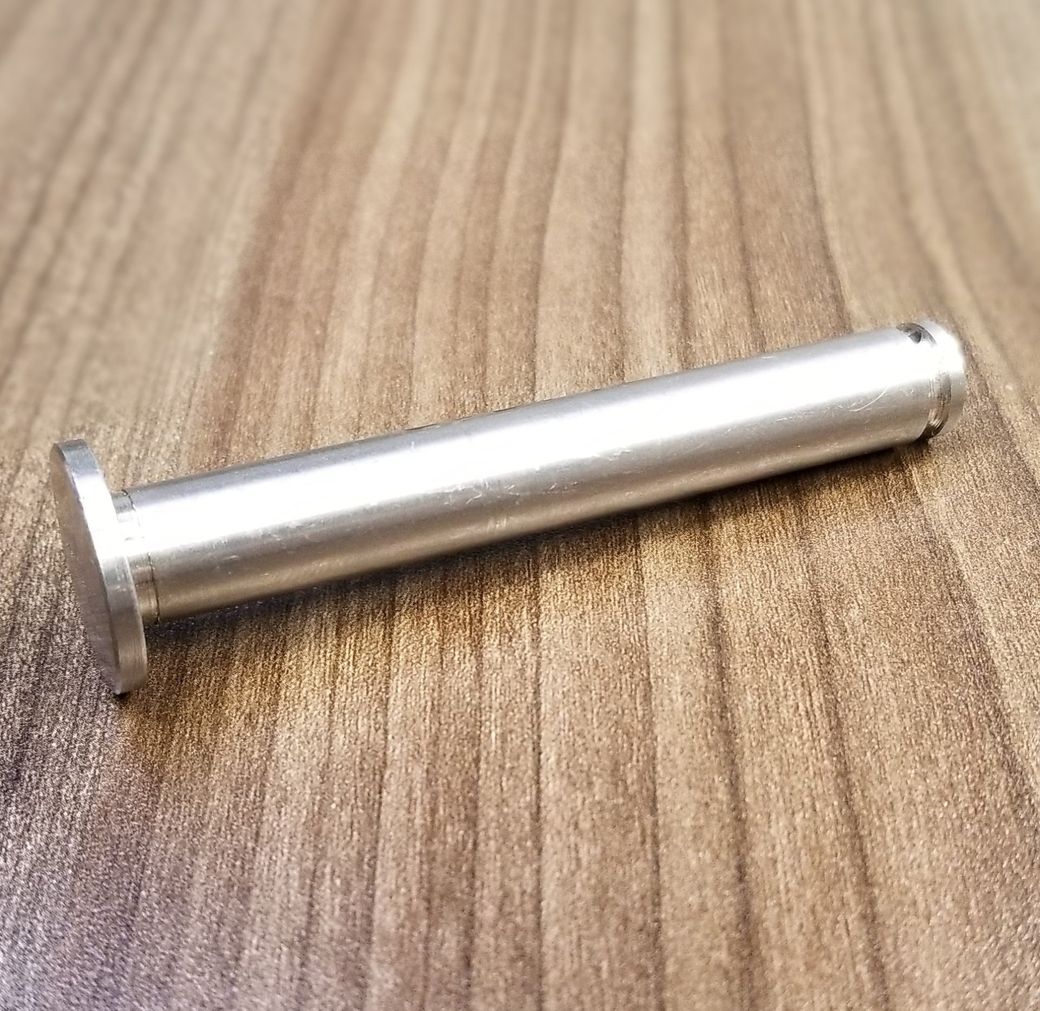 A stainless steel pin is sitting on a wooden table