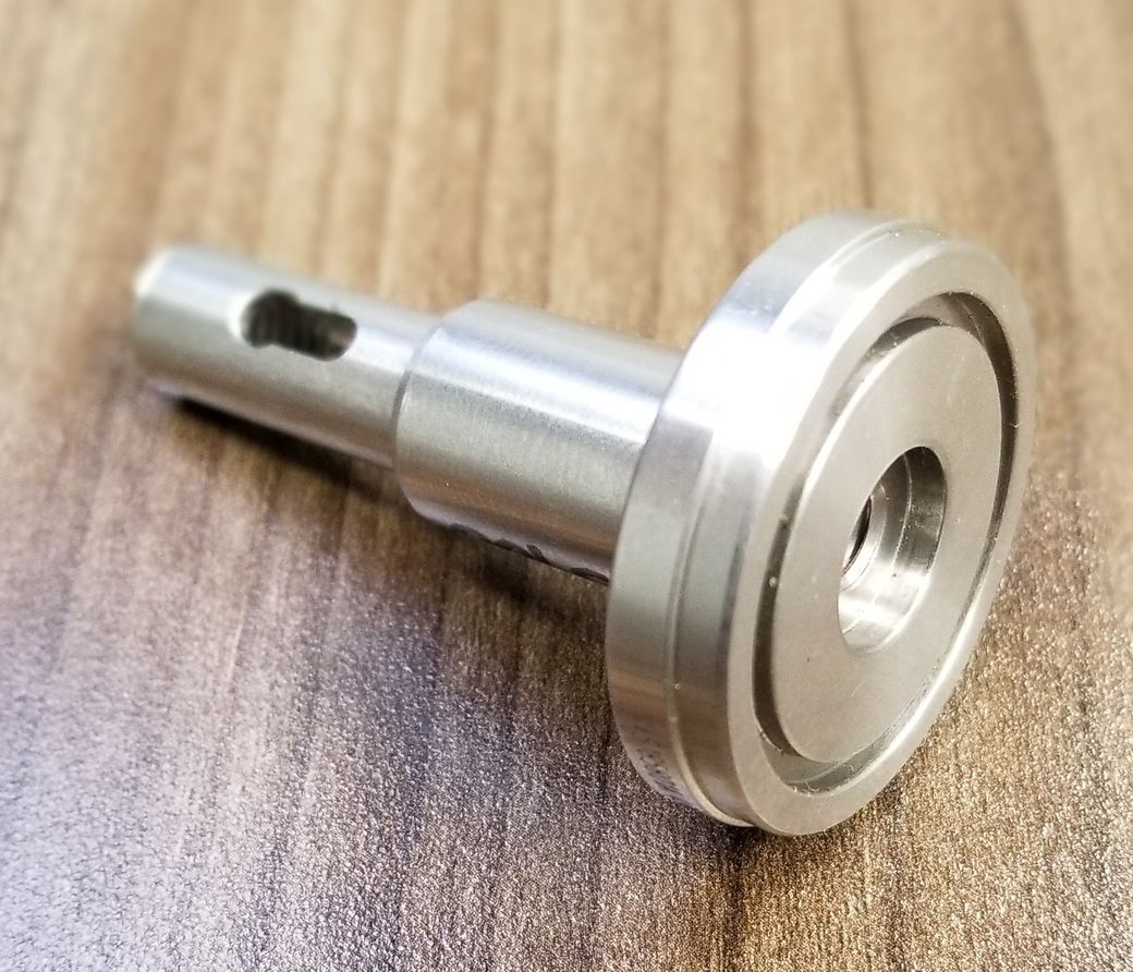 A metal object with a hole in the middle is sitting on a wooden table.