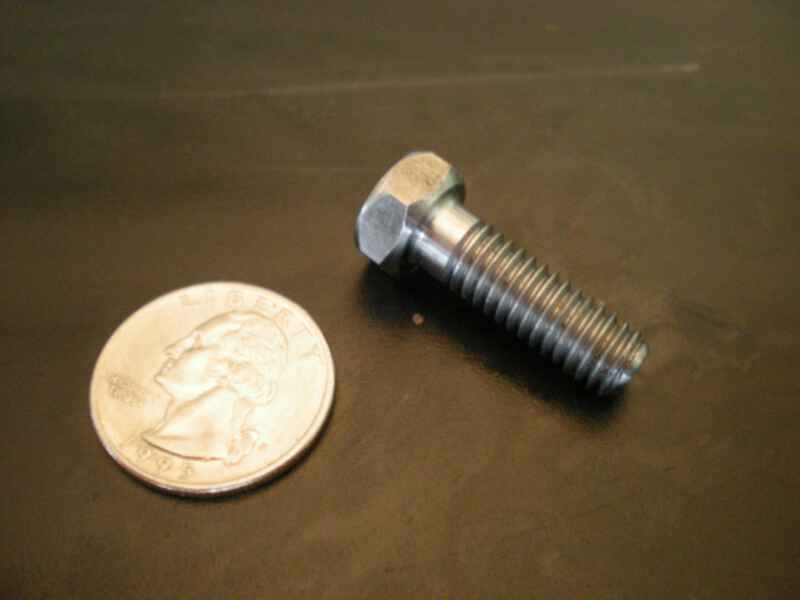 A screw next to a quarter on a black surface